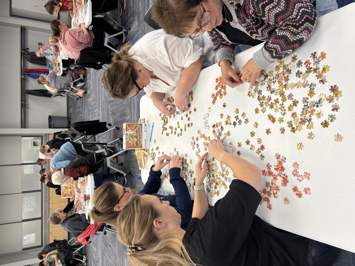 women doing a puzzle on a white table